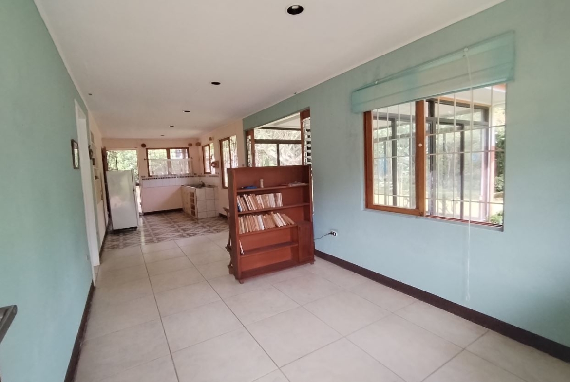 Long bright hallway with light blue walls, tiled floor, and a wooden bookshelf in the middle; large windows along the right wall.]