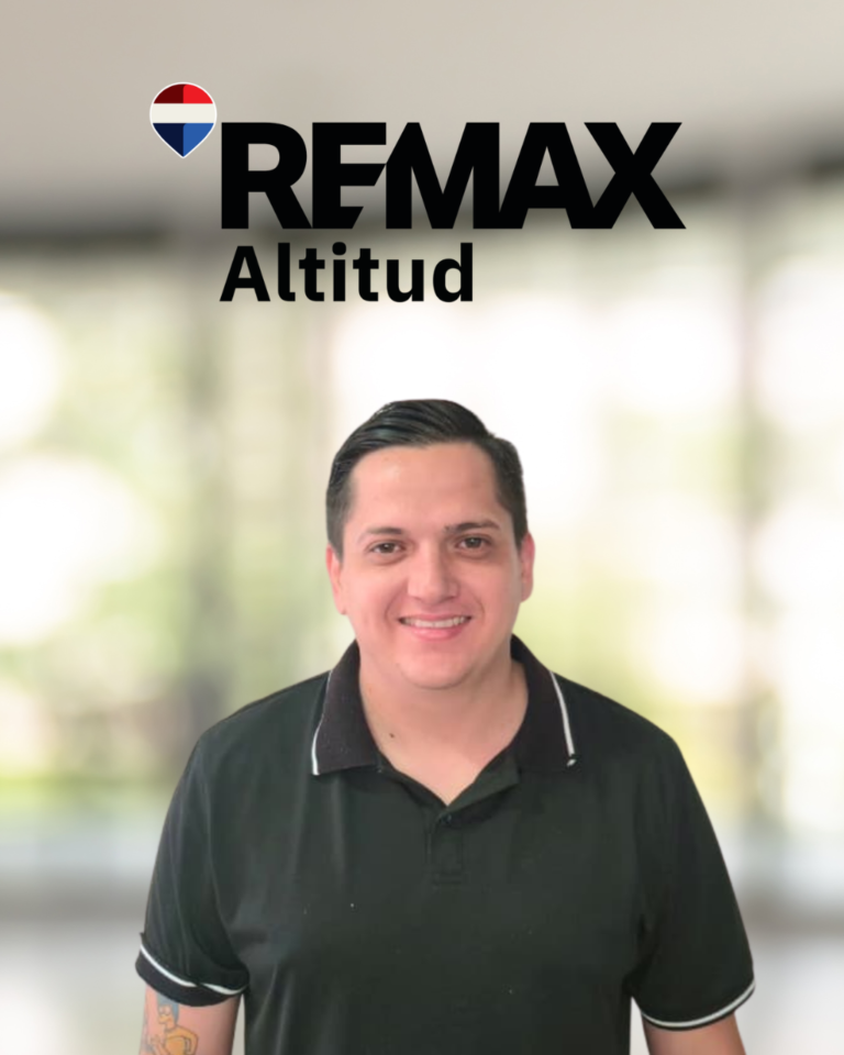 Portrait of a smiling man in a black polo shirt with the REMAX Altitud logo in the blurred background behind him.