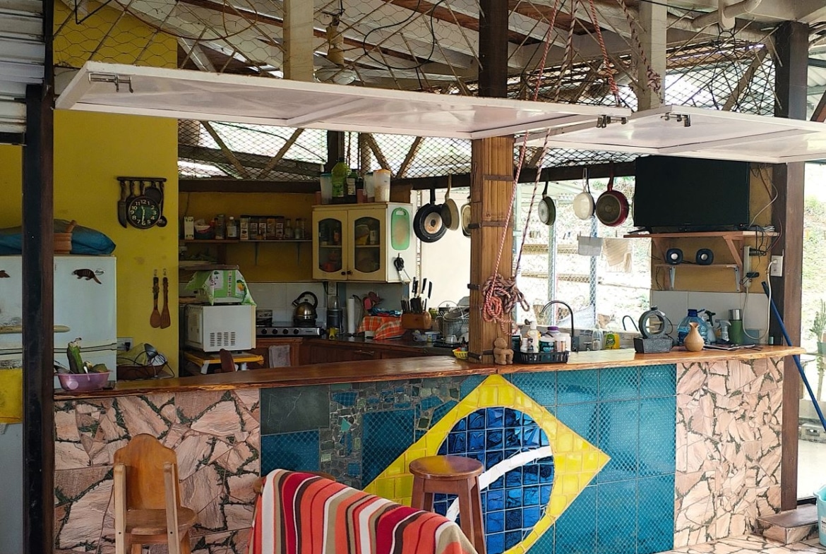 Open-air kitchen/bar with a mosaic Brazilian flag on the counter front and hanging pots above the bar