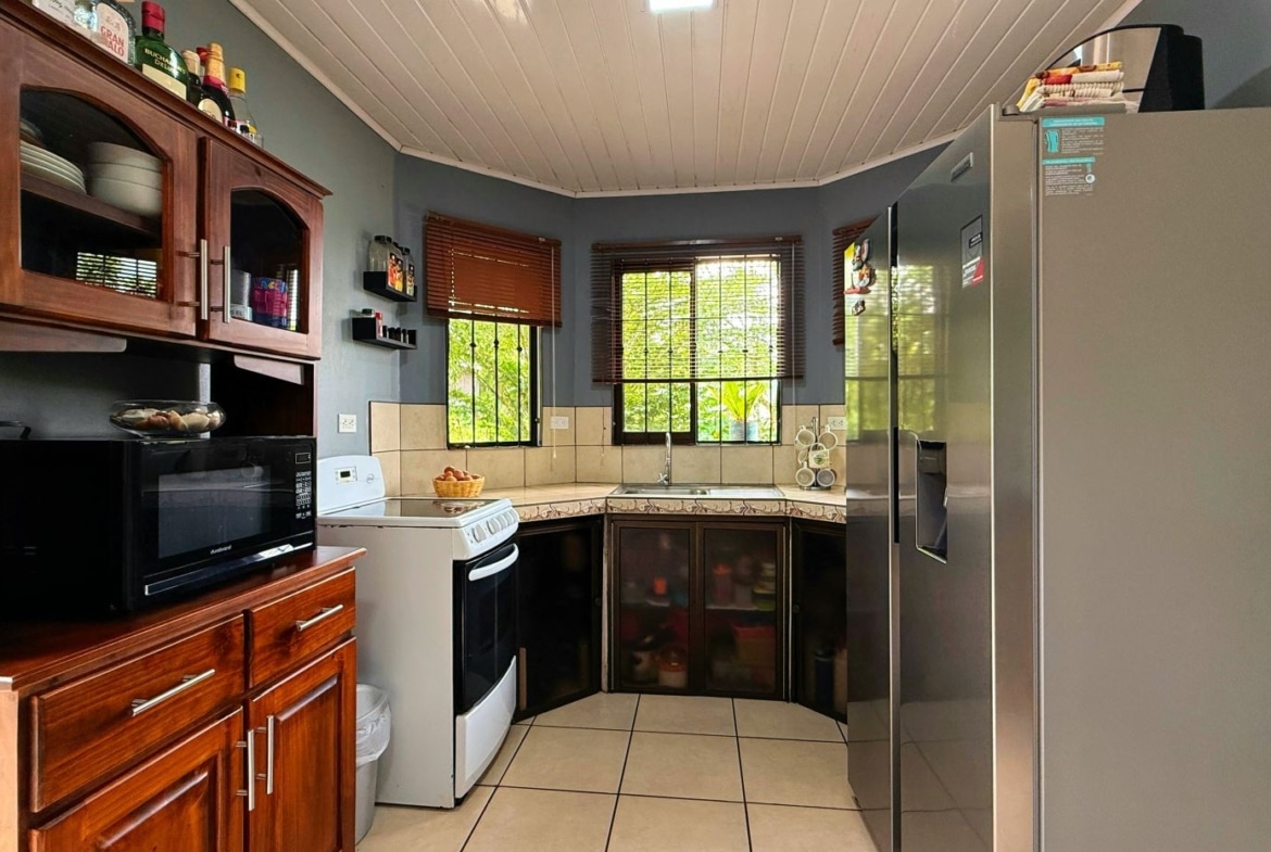 Cozy kitchen with dark wood cabinets, white appliances, and two windows with wooden blinds.