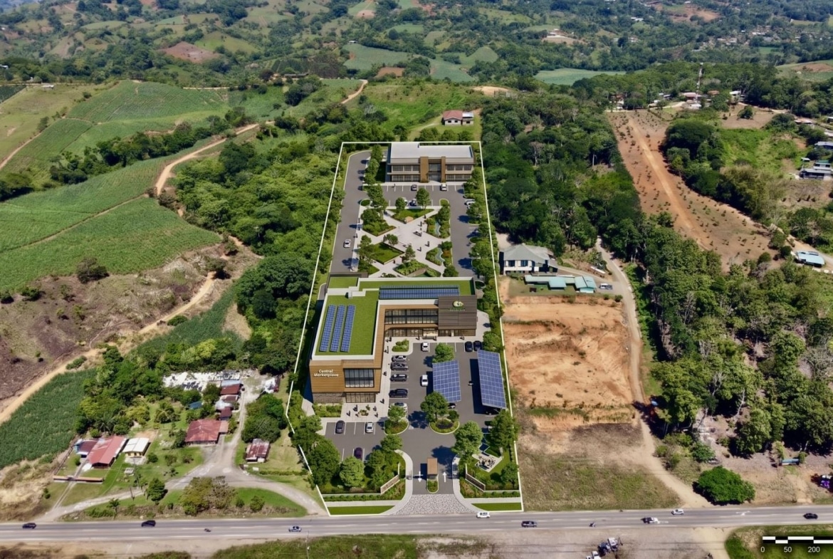 Aerial rendering of a long rectangular development site with a modern two-story building, parking, and landscaped courtyards surrounding it.