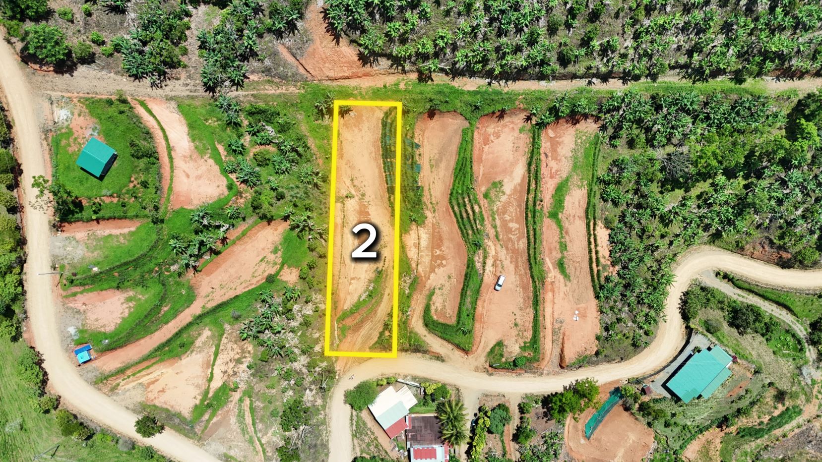 Aerial view of terraced farmland with a yellow-outlined rectangle labeled 2 amid green fields and dirt paths.