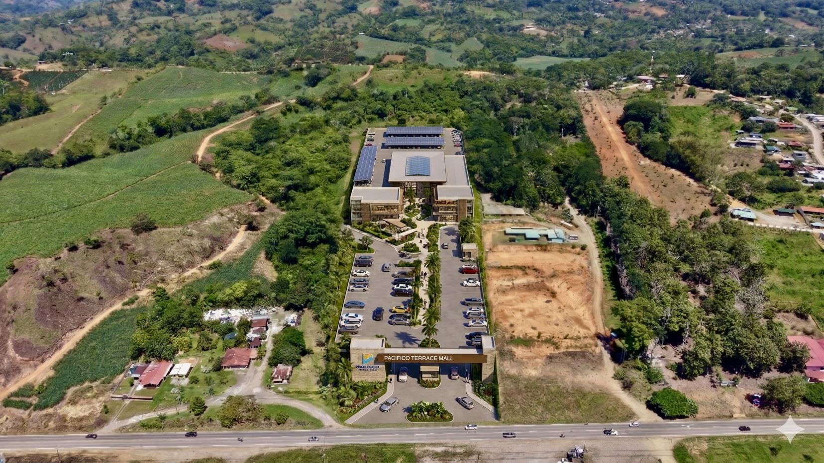 Aerial view of Pacifico Terrace Mall in a green hillside setting with a large parking lot and solar panels on the roof.