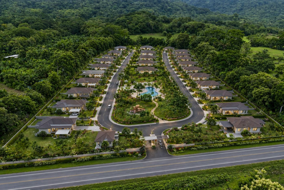 Aerial view of a gated residential community with symmetrical rows of single-story homes, a central landscaped park, and a kidney-shaped pool.