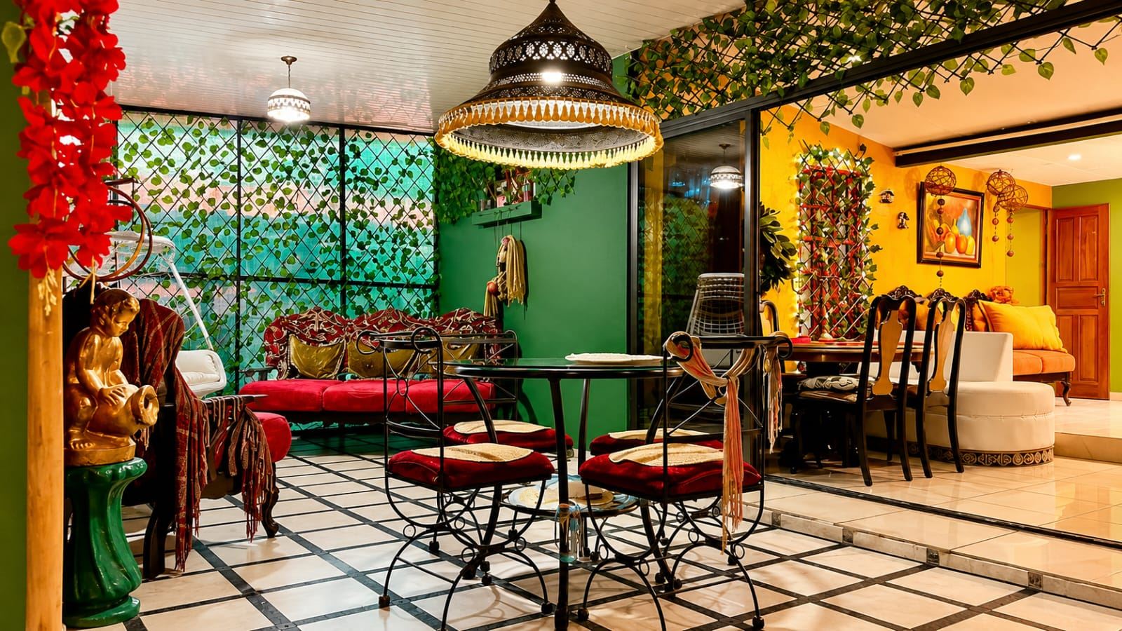 Colorful indoor dining area with a glass table and ornate red-cushioned chairs under a decorative hanging lamp