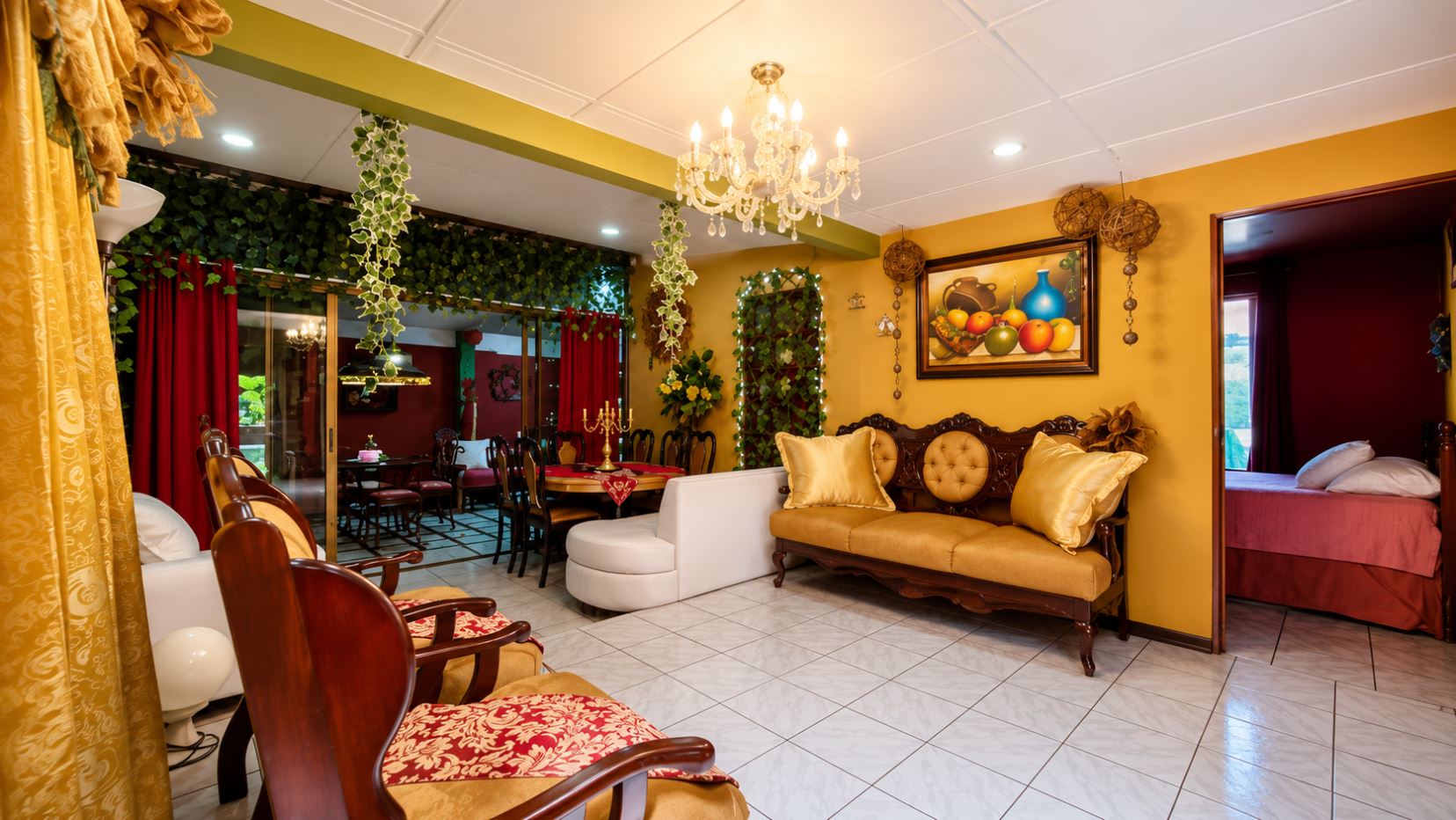 Elegant living room with yellow walls, chandelier, and tufted sofa; potted plants and framed fruit still-life art on wall.